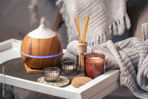 A cozy composition with an aroma diffuser and candles in a home interior.