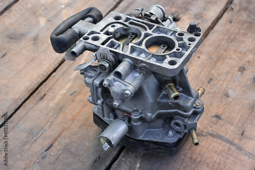 Close-up of a gasoline carburetor. Car repair in the workshop. carburetor isolated. removed from the engine. wooden background.