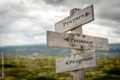 prayers patience progress text quote on wooden signpost outdoors in nature during daytime.