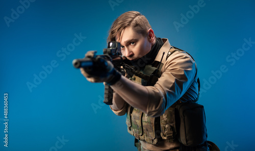 a male special agent soldier in a bulletproof vest with an automatic rifle on a blue background