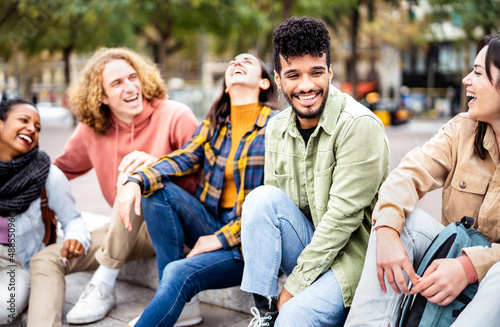 Milenial friends sitting together at city center on life style concept - Happy guys and girls having fun talking around Barcelona street - University students on travel vacation - Bright vivid filter