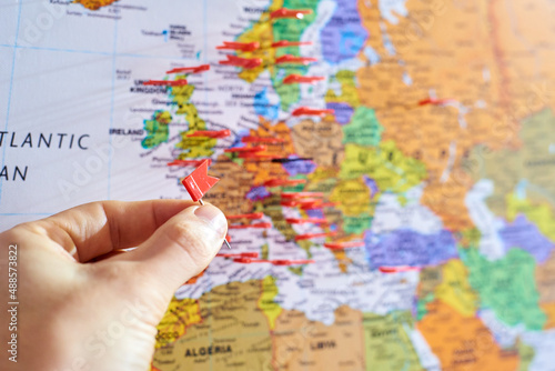 Eine Hand setzt gerade eine Pin Markierung auf eine Landkarte, Ausschnitt liegt auf Europa - Reise, Weltreise