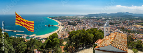 Sea coast of Costa Brava region with panoramic view of the resort Blanes. Wide landscape with scenic of beaches on Mediterranean coast of Spain and flag of Catalonia, top view.