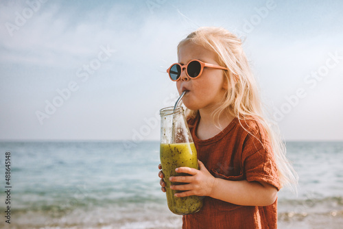 Kid girl drinking smoothie on beach healthy eating lifestyle vegan food breakfast child with glass bottle and reusable metal straw detox beverage summer vacations