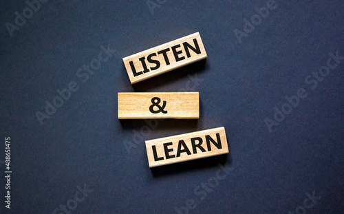 Listen and learn symbol. Concept words Listen and learn on wooden blocks. Beautiful black table black background. Copy space. Business, educational and listen and learn concept.