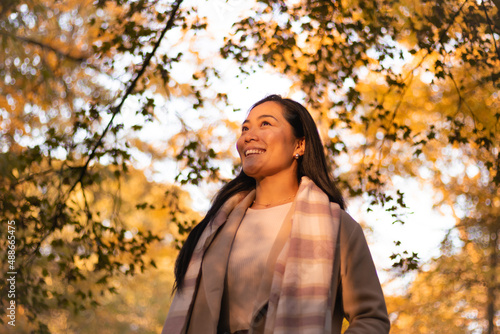 Inspired millennial optimistic with a smile looking into the future, while enjoying the setting sun in a park on a fall day.