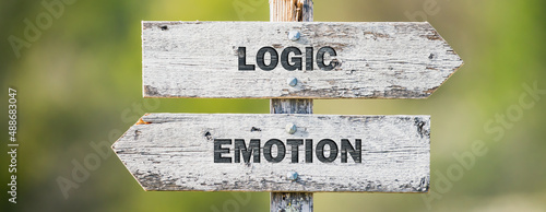 opposite signs on wooden signpost with the text quote logic emotion engraved. Web banner format.