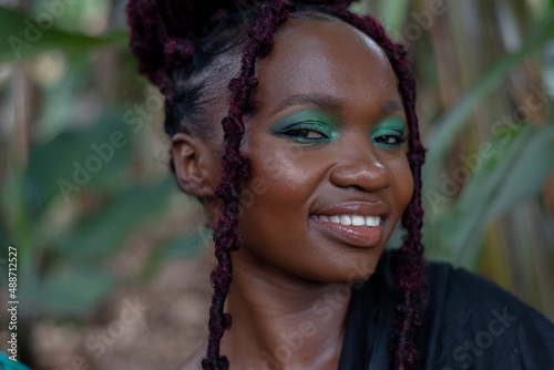 Portrait of a smiling young African woman, in a farm, with long red braids