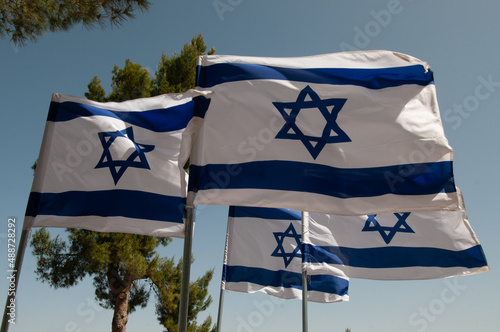 Multiple, large, blue and white flags of the State of Israel rippling in the wind during the observance of Independence and Memorial day holidays at the Har Herzl military cemetery in Jerusalem.