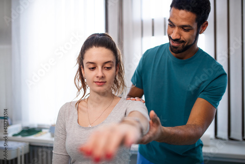Young male physiotherapist examining young woman patient in a physic room