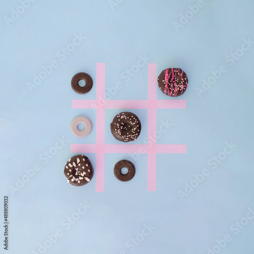 Doughnuts colorful playing Tick Tack Toe with round cookies. Food aesthetic flat lay design idea. Playing game food concept