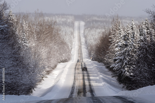 Quebec 216 road, in the region of Chaudière-Appalaches, in winter with a large panoramic view on the snowed forest bordering the partial snowed road.