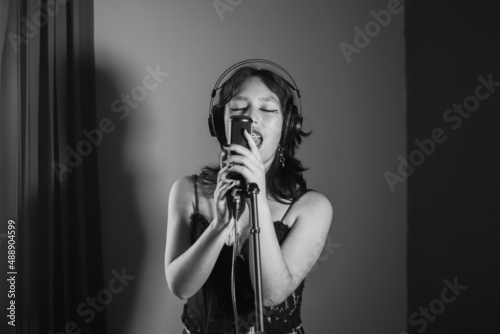 Mujer joven cantando contenta en un estudio musical a blanco y negro