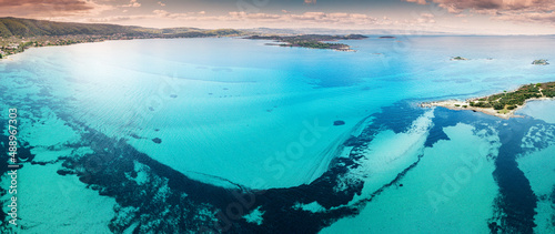Aerial view of the paradise seashore with various shades of turquoise water. Coral reefs and secluded sandy beaches near the resort village of Vourvourou in Sithonia, Halkidiki.