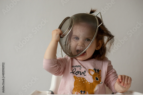 Baby girl play with colander and have fun.