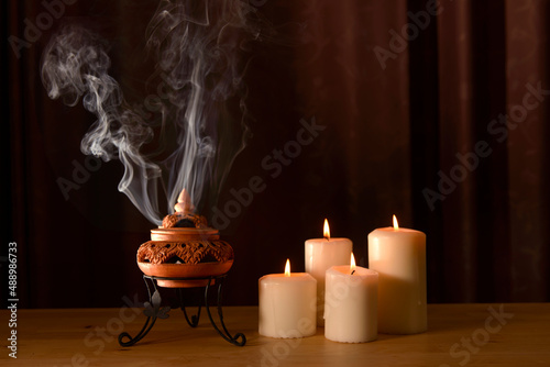 incense burning in an incense burner with candles on the table for praying Buddha or Hindu gods to show respect.Religion concept.