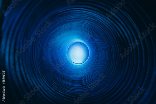 Blur glow background. Galaxy portal. Moonlight radiance. Defocused neon blue color lunar light sphere in ridged swirl texture tunnel on dark black.