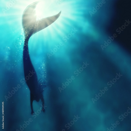 A silhouette shot of a mermaid swimming in solitude in the deep blue sea - ALL design on this image is created from scratch by Yuri Arcurs team of professionals for this particular photo shoot