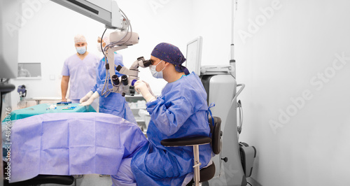 A surgeon looking through a surgical microscope and operating on his patient
