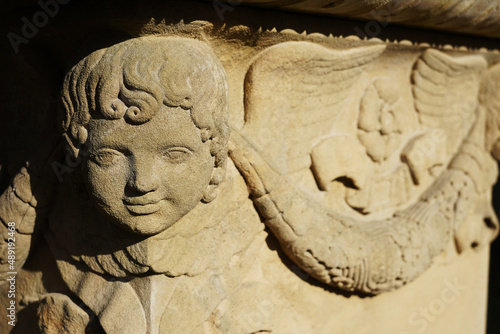 Ein lächelnder Engel Kopf an der Ecke eines Grabsteins aus der Biedermeier Zeit. Der Stein steht im Hoppenlauf Friedhof, die älteste Nekropole der Stadt Stuttgart. 
