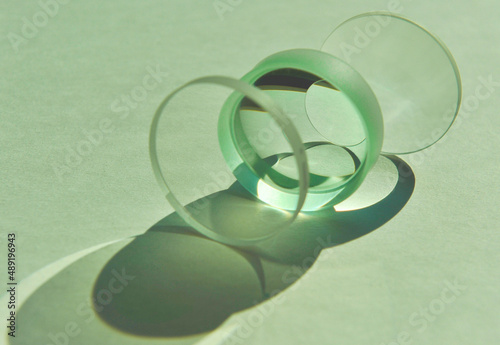 Closeup of sunlight through clear circular convex and concave lens with different focus lengths overlapping. Mixture refection and refraction of light create artistic shade and shadow on white paper