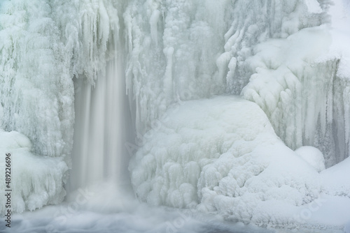 Winter landscape of a cascade captured with motion blur and framed by ice, Comstock Creek, Michigan, USA