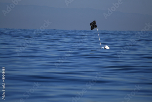 Bandiera nera realizzata con un sacco della spazzatura, in mezzo al mare, per indicare la posizione di una boa e palamito sott'acqua