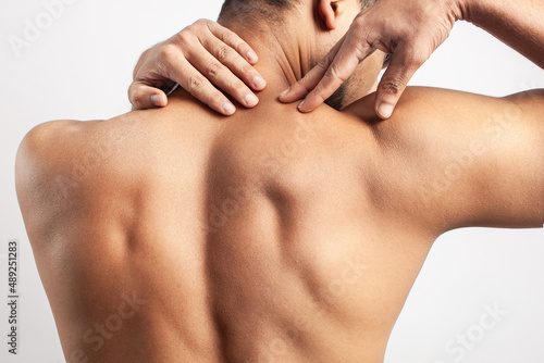 trapezius muscle pain, muscular man showing his back shoulder muscle