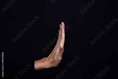 Hand of Caucasian person showing stop sign on black background. Domestic physical and psychological abuse, relative aggression, gaslighting and social injustices. Copy space.