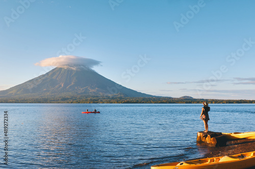 Young woman wearing hat standing on the shore of the lake with beautiful view to Concepción volcano in Ometepe island, Nicaragua.