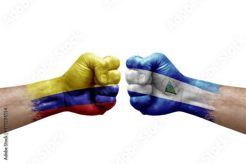 Two hands punch to each others on white background. Country flags painted fists, conflict crisis concept between colombia and nicaragua