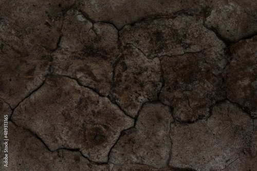 Texture of the dried earth. Dark brown background with cracks and hollows. Drought and lack of moisture in the soil. The consequences of abnormal heat. Environmental disaster. Global warming.