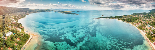 Aerial panoramic scenic view of azure blue lagoon and paradise bay with majestic patterns on a sea shelf. Resort village of Vourvourou on Sithonia peninsula in Halkidiki, Greece