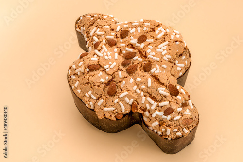 Colomba Pasquale on light brown background, typical italian easter cake with sugar glaze and with almonds. Easter Dove in english.