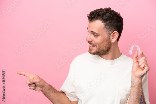 Brazilian man holding invisible braces pointing to the side to present a product