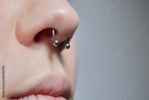 Closeup of a young woman's visage with piercing septum hanging from her nose.