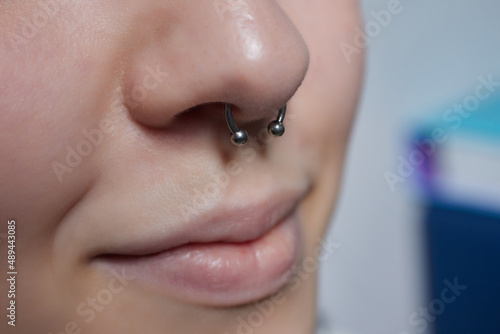 Closeup of a young woman's visage with piercing septum hanging from her nose.