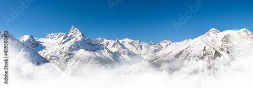 Panoramic view of winter snowy mountains in Caucasus region in Russia with blue sky