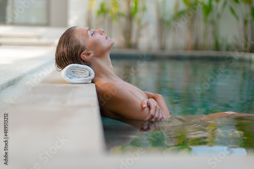 Beautiful young girl relaxes in the pool, spa.