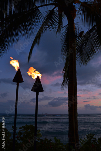 Two torches light a tropical night along Waikiki Beach
