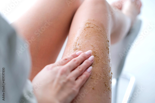 A woman applies scrub on her legs. Women use anti-cellulite cream. female body care. Cosmetology, massage, spa cosmetics.