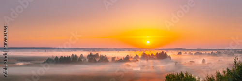 Amazing Sunrise Sunset Over Misty Landscape. Scenic View Of Foggy Morning Sky With Rising Sun Above Misty Forest And River. Early Summer Nature Of Eastern Europe. Panorama.