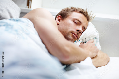 He needs plenty of sleep. Young guy sleeping deeping in bed at home.