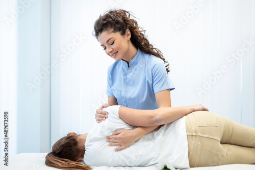 Close up of female osteopath doing shoulder blade therapy on young woman.