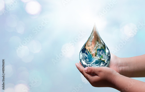 World water day. A globe in the shape of a drop of water falling onto the boy's hand on blue sea background. Elements of this image furnished by NASA .