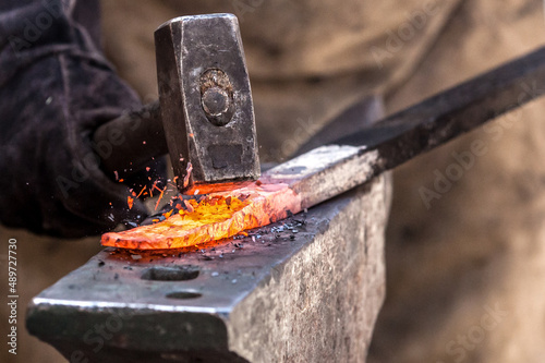 A Sword smith shaping a blade on an anvil