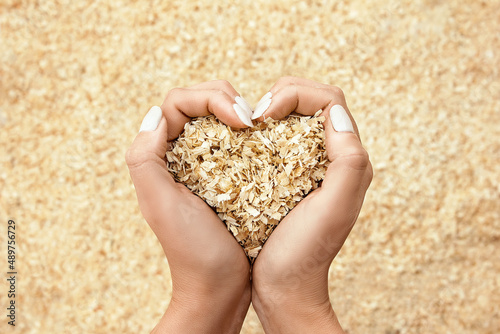beautiful female hands, in the shape of a heart, carefully, lovingly hold a handful of wooden sawdust on a blurred background with a lot of sawdust. concern for nature. Protecting trees. ecology. warm