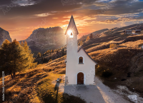 South Tyrol, Italy - The setting sun is shinning through the Chapel of San Maurizio (Cappella Di San Maurizio) at the Passo Gardena Pass in the Italian Dolomites at autumn with warm sunlight