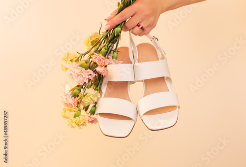 Fashion - spring or summer footwear for woman. White dress sandals shoes on beige background.