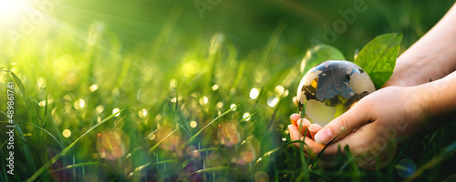  Earth Day.Hand holding crystal earth globe. Environment day, save clean planet, ecology concept.Renewable energy-based green businesses can limit climate change and global warming.